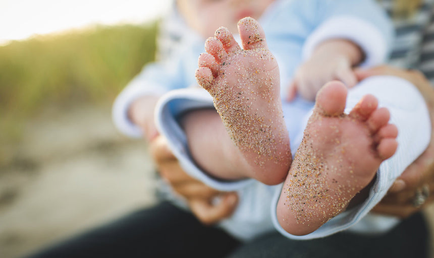 a baby with sandy feet