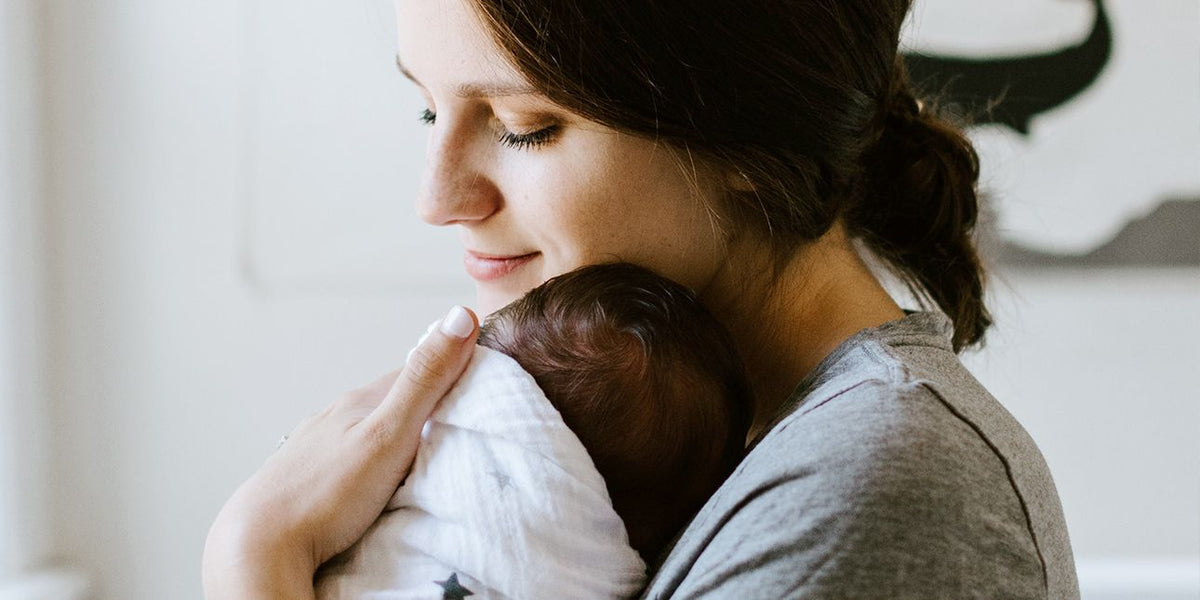 a mother cuddling her baby wrapped in a blanket