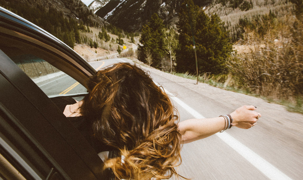 a girl leaning out the car window on a road trip