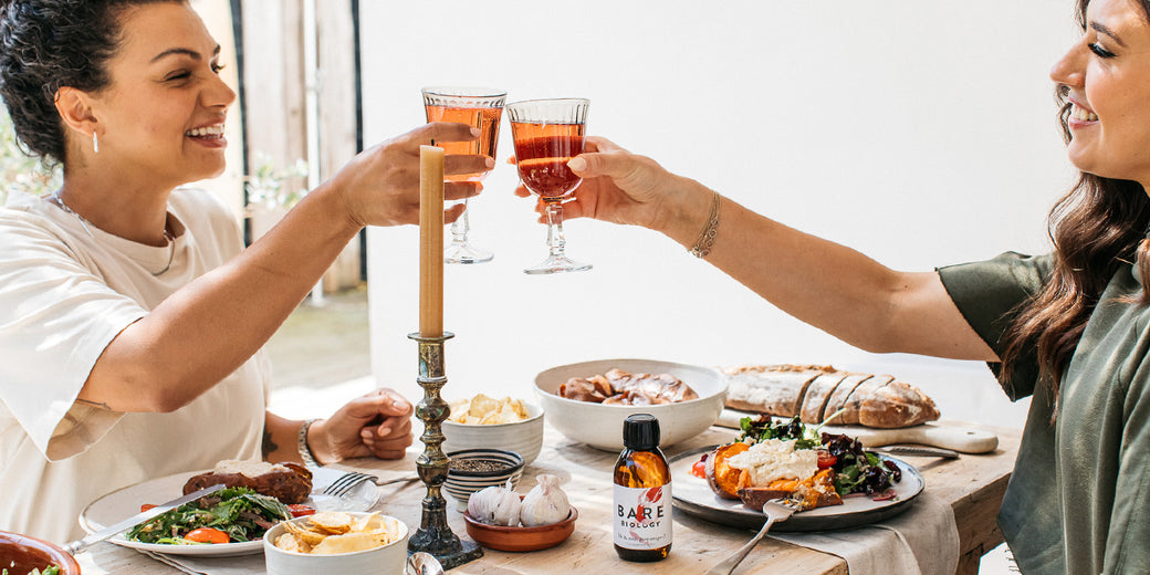 two women sipping wine at a dinner table with bare biology life & soul omega 3 fish oil