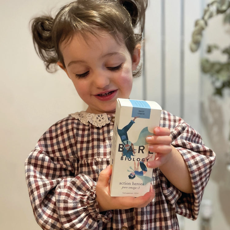 little girl holding bare biology omega-3 liquid for kids