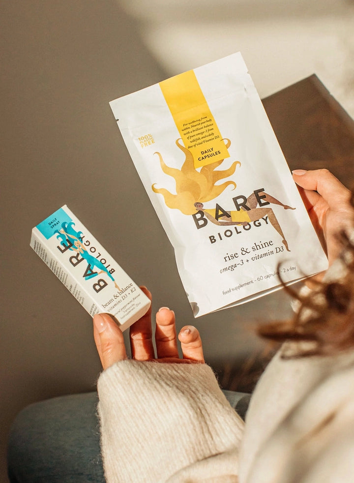 woman holding bare biology beam and balance and rise and shine supplements