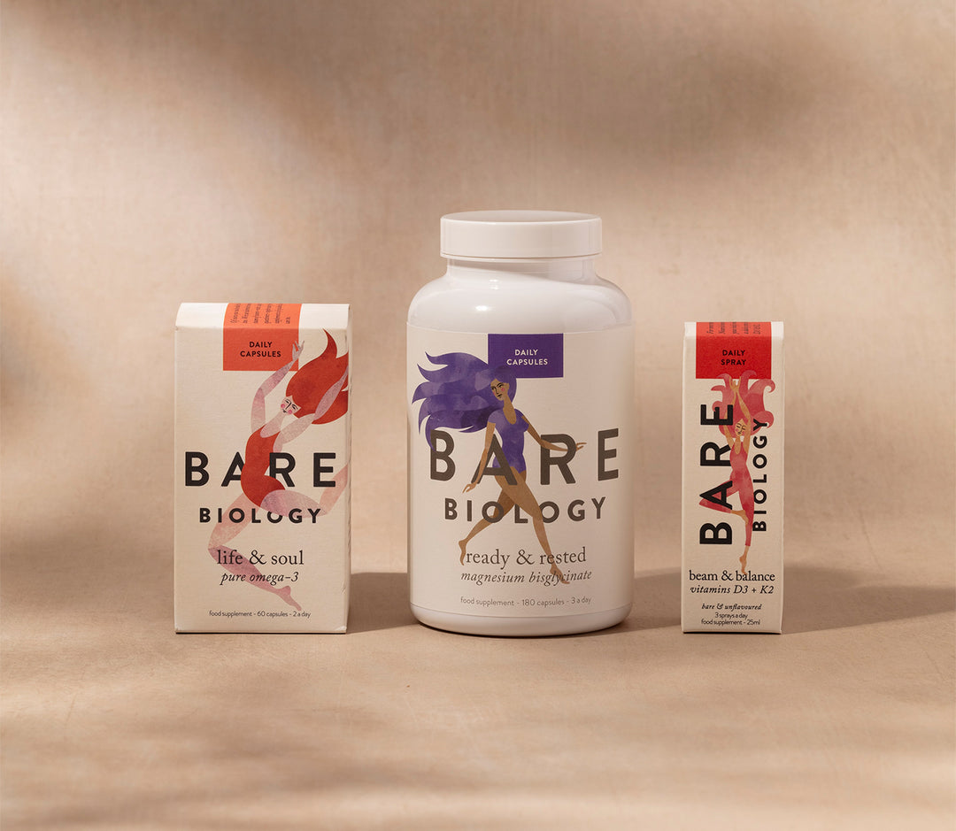 Range shot of Bare Biology omega-3 capsules, vitamin D and magnesium capsules on a beige background with shadows