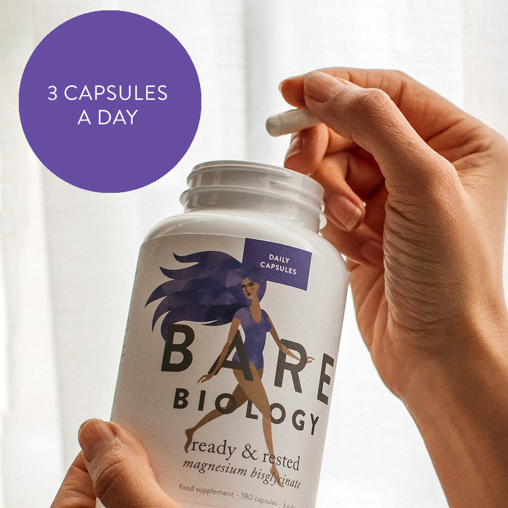 Hand holding a capsule and the jar of Bare Biology's  Ready and Rested magnesium capsules. In the top corner there's a purple roundel with the messaging 3 capsules a day. 