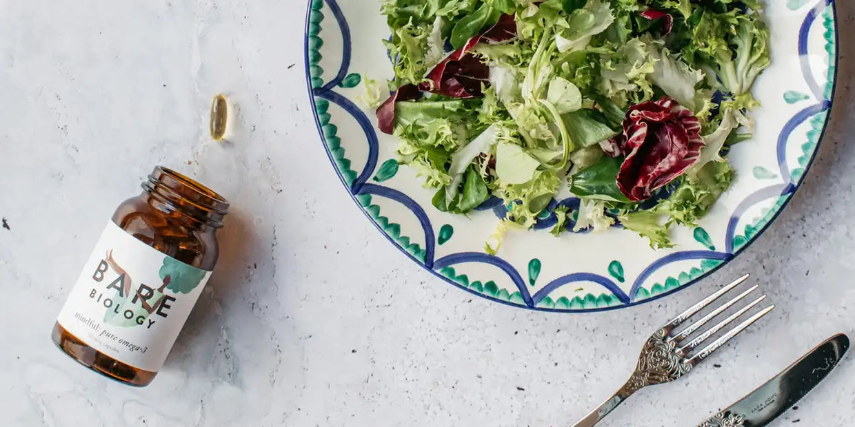 bare biology mindful omega 3 capsules for brain health next to a plate of salad leaves