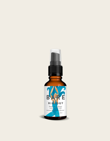 The Vitamin D3 with Vitamin K2 Spray by Bare Biology comes in a small amber bottle with a black spray cap and a white label featuring a blue wave design. Infused with peppermint oil, it is set against a plain, light beige background, enhancing its refreshing appeal.